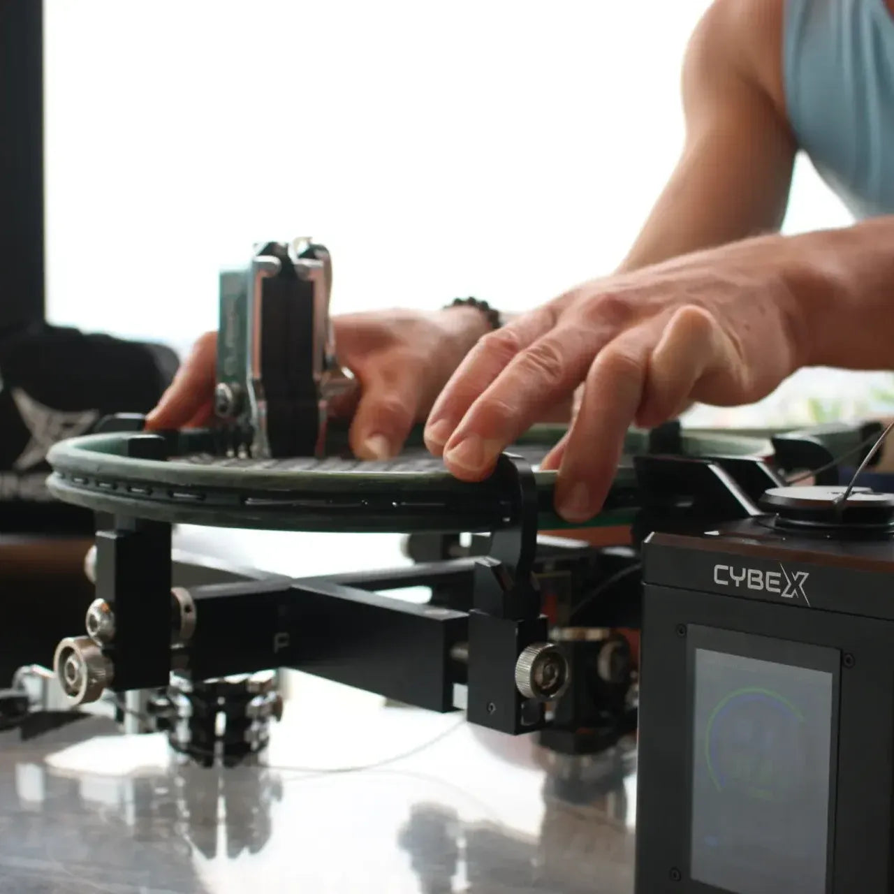 Hands stringing a racquet on a Pro Stringer CybeX